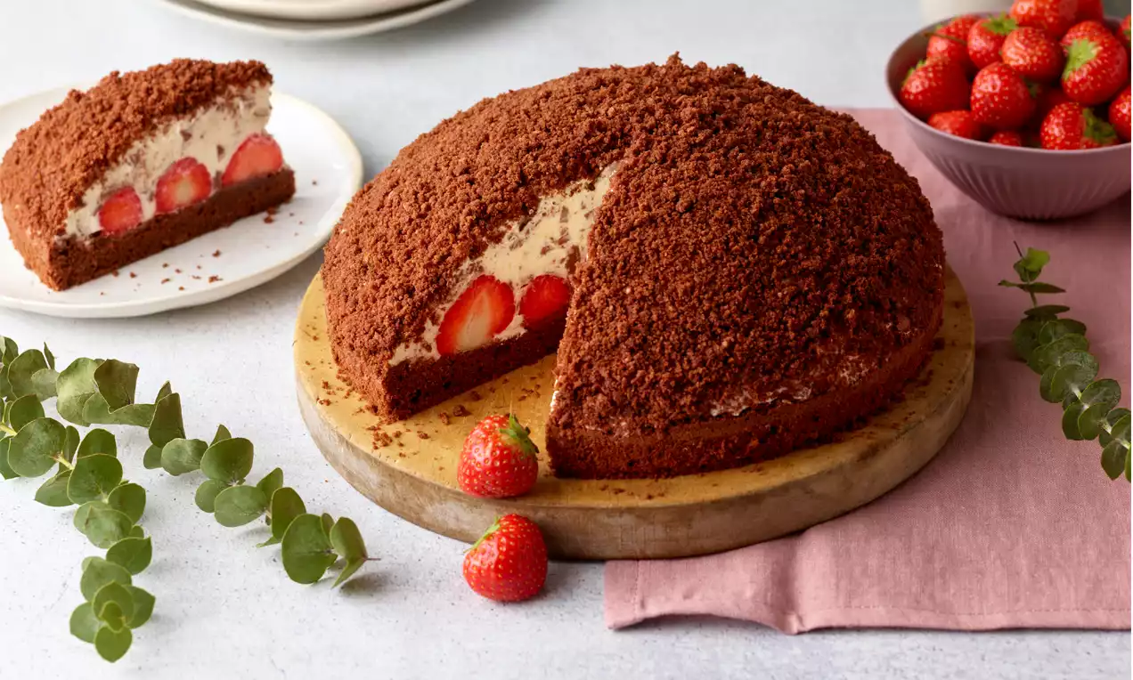 Dunkler runder Kuchen mit einer Füllung aus Schlagobers, Raspelschokolade und Erdbeeren.