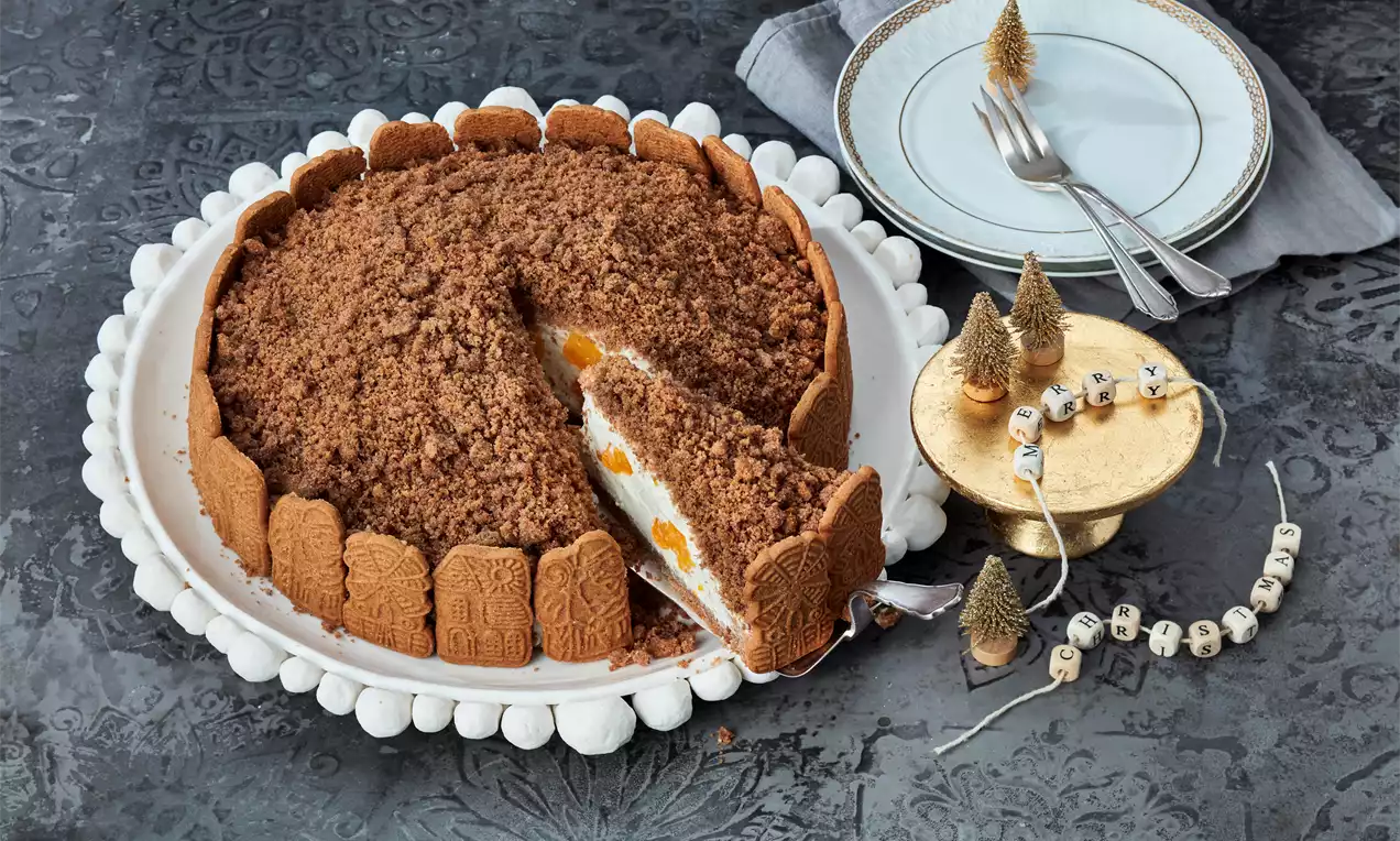 Spekulatius-Maulwurfkuchen mit hellweißer Sahnefüllung und gelben Fruchtstücken, umrandet von Spekulatius, auf weißer Tortenplatte