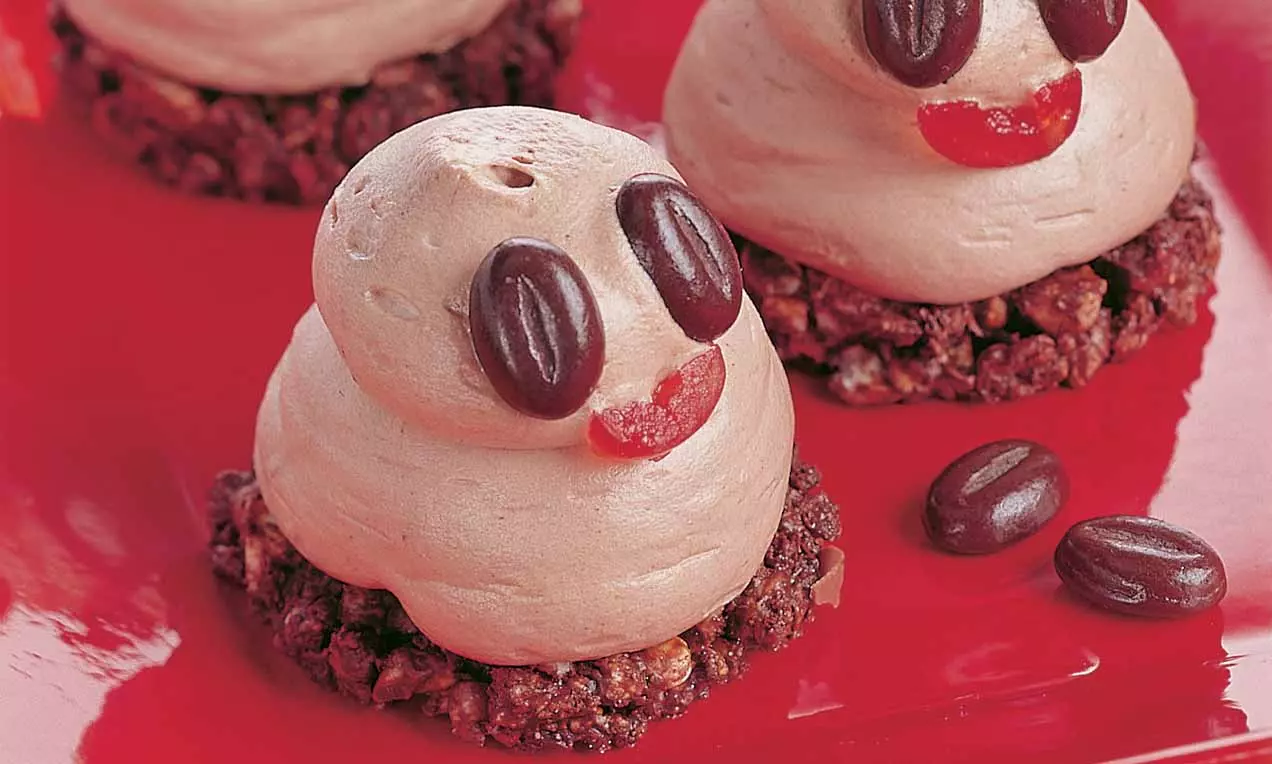 Schoko-Cappuccino-Törtchen mit cremigem, hellbraunem Topping auf dunklem Schokokrümelboden, dekoriert mit Kaffeebohnen und roten Gelee-Akzenten