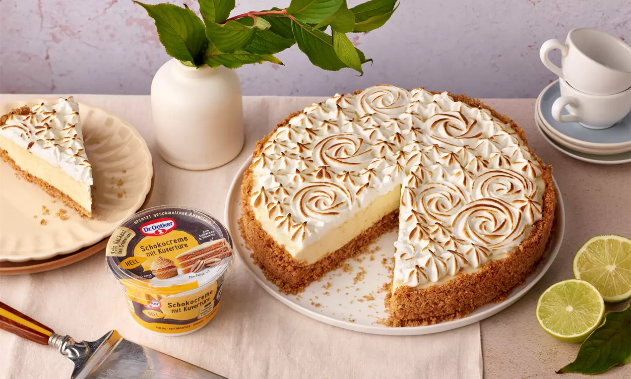 Weißer Schoko-Cheesecake mit goldbraun karamellisierter Baiseradecke, cremiger Füllung und knusprigem Boden auf weißem Teller arrangiert