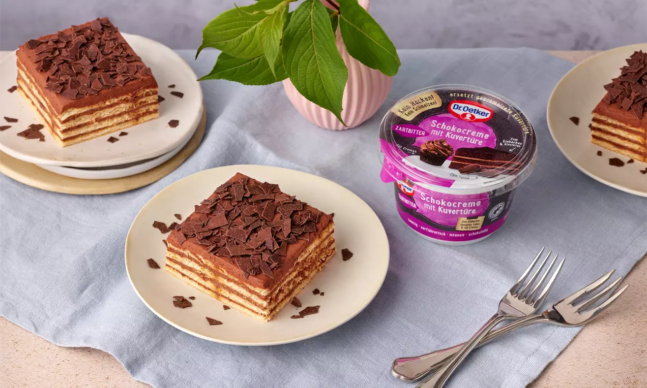 Butterkekskuchen mit geschichteten Keksen und cremiger Schokoladenfüllung, dekoriert mit Schokoraspeln, serviert auf weißen Tellern